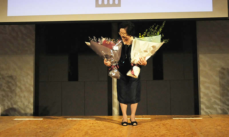 旭日中授章を祝う花束を手に、笑顔を見せる谷本榮子同窓会名誉会長